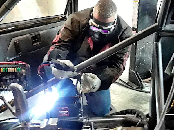 A photo of John welding on a race car